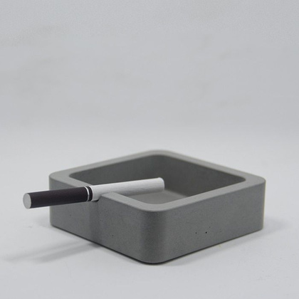 A minimal square grey ash tray with softly rounded edges
