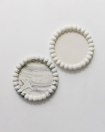 Two small round white trinket dishes with a beaded rim