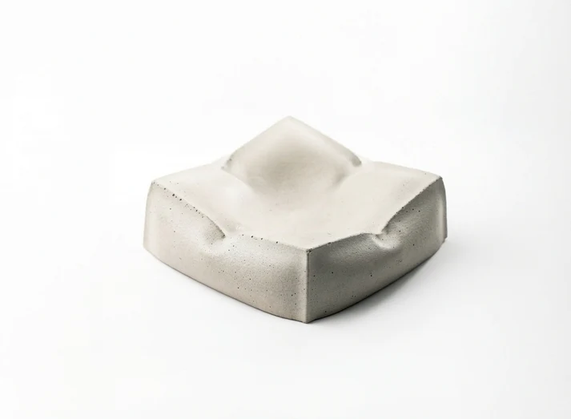 A sculpted square white coaster shaped like a soft pillow